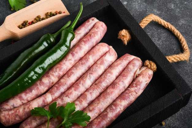 Raw sausages Bratwurst or sausages with ingredients on cutting board with spices on a stone background with copy space Food cooking background Top view