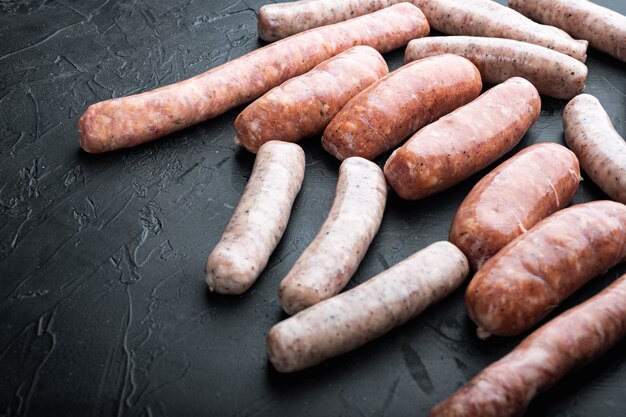 Raw sausages on dark background