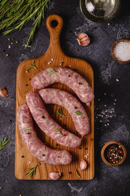 Raw sausages and ingredients for cooking on a black stone table