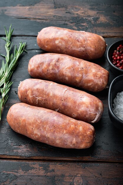 Raw sausages on old dark wooden background