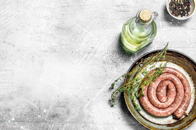 Raw sausages in a pan with thyme