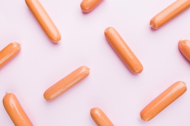 Raw sausages in polyethylene shell isolated on pink background. Top view, flat lay. Pin-up style background