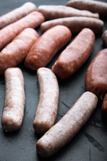 Raw sausages set, on black table.