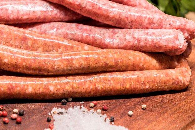 Raw sausages with chilli and herbs on a wooden board with spices