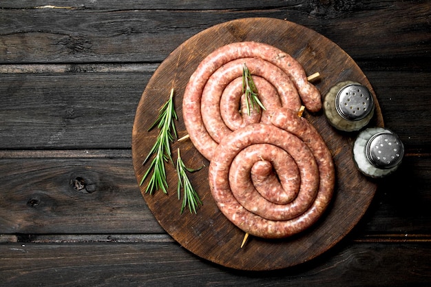 Raw sausages with herbs on a wooden Board