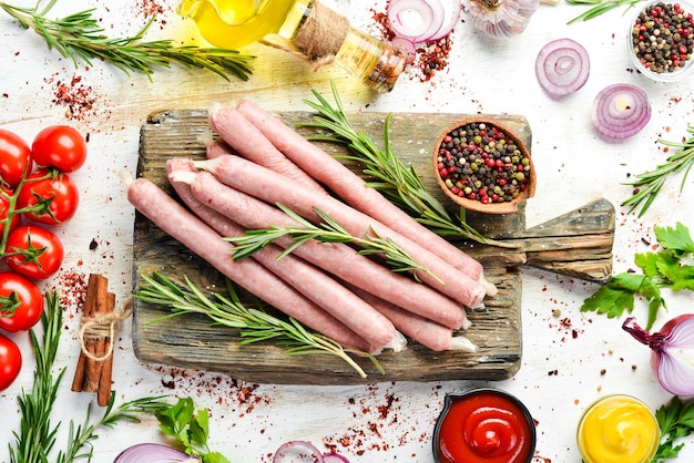 Raw sausages with rosemary and vegetables Top view Free space for your text