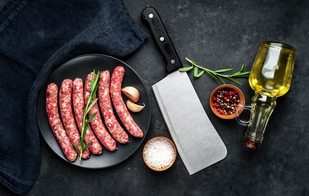 raw sausages with spices on a black plate on a stone background