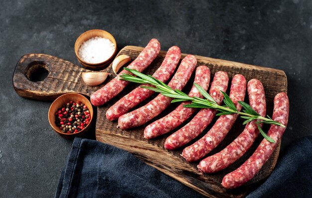 raw sausages with spices on a cutting board on a stone background