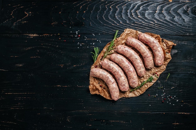 Raw sausages with spices and rosemary on cutting board Cooking ingredients Natural healthy food concept top view