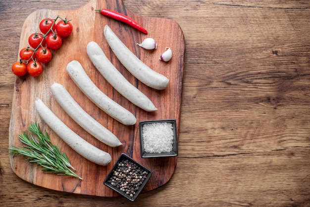 Photo raw sausages with spices on a rustic background