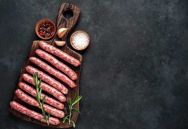 Raw sausages with spices on a wooden board