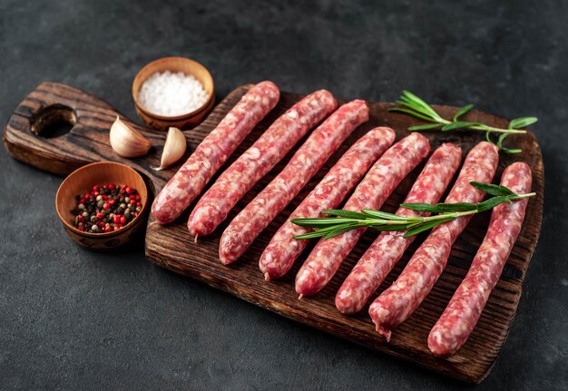 Raw sausages with spices on a wooden board