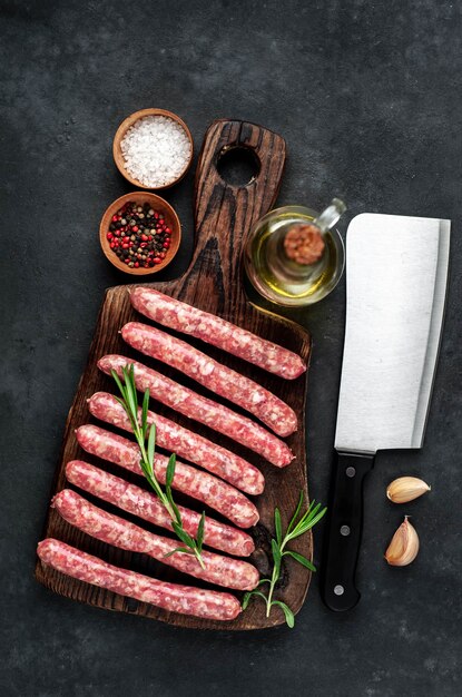 Raw sausages with spices on a wooden board