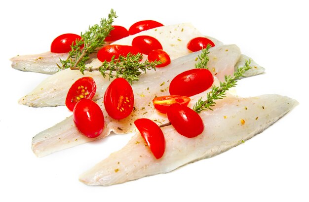 Raw sea bass fillets with cherry tomatoes on white