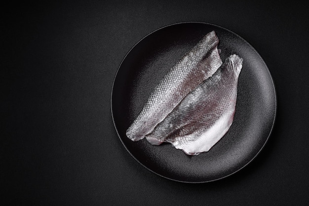 セラミック プレートに塩スパイスとハーブを添えた生のスズキの魚の切り身