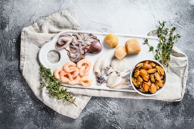 Raw seafood mix on a ceramic chopping Board. Top view.