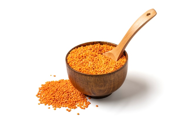 Raw seeds of orange lentils in wooden bowl spoon isolated