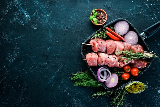 Raw shish kebab. Barbecue Meat Spices and Herbs. On a black stone background. Top view. Free copy space.