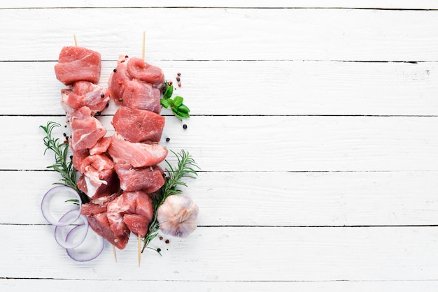 Raw shish kebab barbecue Meat with spices and herbs On a white wooden background Top view Free copy space