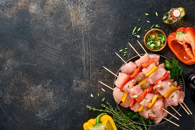 Raw shish kebab on wooden board, spices, herbs and vegetables on dark grey background. Barbecue Raw ingredients for goulash or shish kebab. Top view. Free copy space.