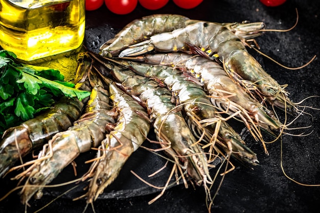 Raw shrimp on a stone board with parsley and tomatoes