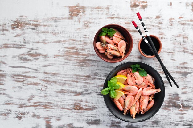 Raw shrimp with lemon on the plate on a white background Wooden Top view Free copy space