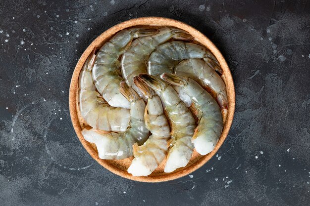 Raw shrimps in a plate on the dark gray