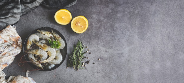 Gamberi crudi su ciotola nera e fondo scuro, frutti di mare freschi di gamberetti