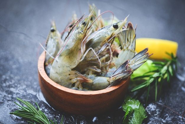 Photo raw shrimps prawns on ice in bowl, fresh shrimp seafood with herbs and spice