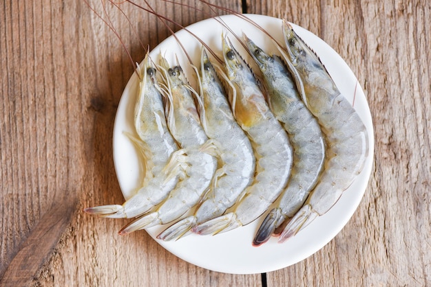 Сырые креветки, креветки на белой тарелке, свежие морепродукты из креветок для приготовленной еды - вид сверху