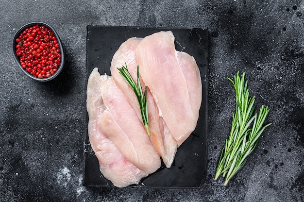 Raw sliced chicken breast fillet steaks on a marble board