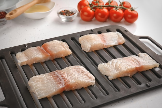 Raw slices of fish fillet on broiler pan in kitchen