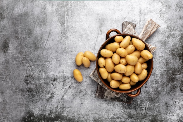 Photo raw small potatoes in a cast iron skillet on a beton background