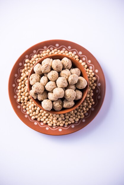 Photo raw soya chunks soy meat for vegans isolated on wooden table in a bowl or in heap form