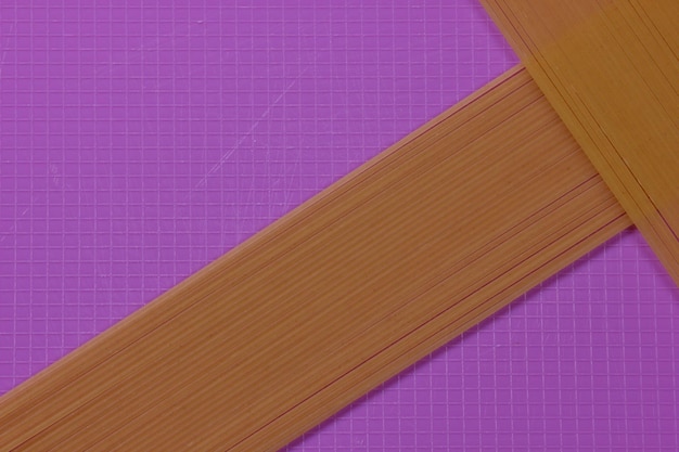 Raw spaghetti on a purple background Vegetarian food concept Closeup of an Italian pasta View from above