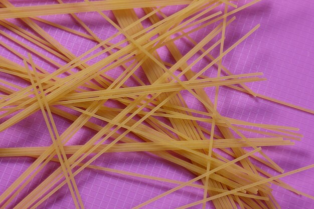 Raw spaghetti on a purple background Vegetarian food concept Closeup of an Italian pasta View from above