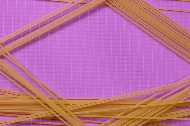 Raw spaghetti on a purple background Vegetarian food concept Closeup of an Italian pasta View from above