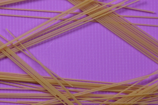 Raw spaghetti on a purple background Vegetarian food concept Closeup of an Italian pasta View from above