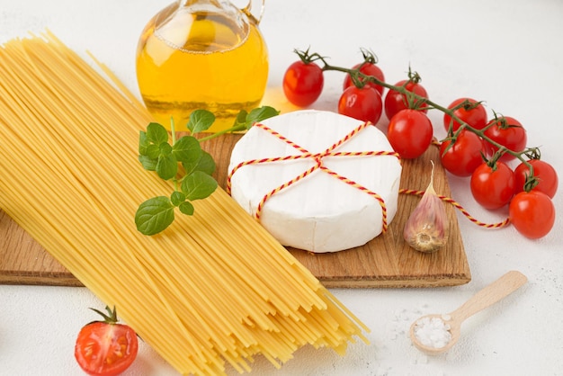 Сырые спагетти с помидорами черри, сыром камамбер, маслом и чесноком