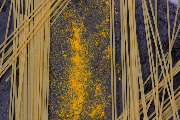 Raw spaghetti with yellow spices on a dark background Closeup of an Italian pasta View from above