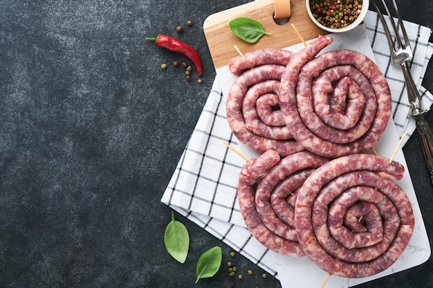 Raw spiral pork sausages Fresh pork sausages tasty twisted spiral for bbq on white stand with spices and herbs for Octoberfest party dinner on gray background Top view Oktoberfest set