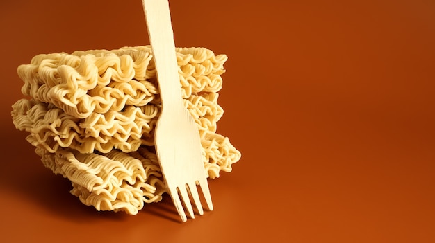Raw square-shaped instant noodles with a wooden fork, stacked in a stack of three servings. pasta, for the preparation of which it is enough to pour boiling water and wait a few minutes. Copy space.
