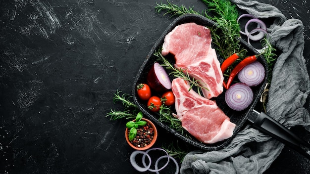 Photo raw steak on the bone meat with spices and herbs on a black stone background top view free copy space