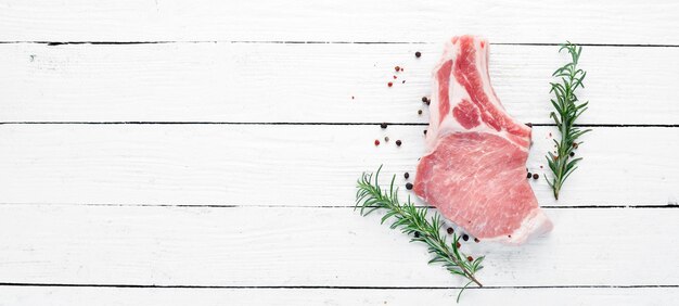 Raw steak on the bone Meat with spices and herbs On a white wooden background Top view Free copy space