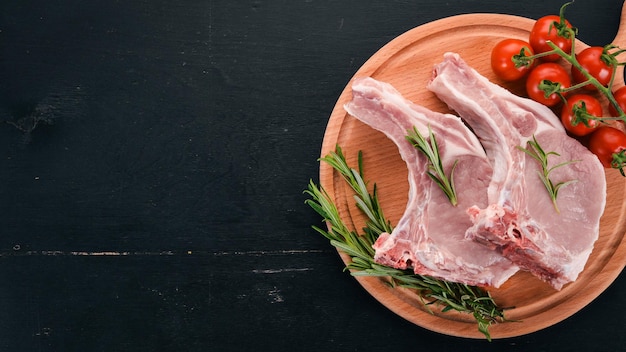 Raw steak on the bone with spices and vegetables On a wooden background Top view Copy space