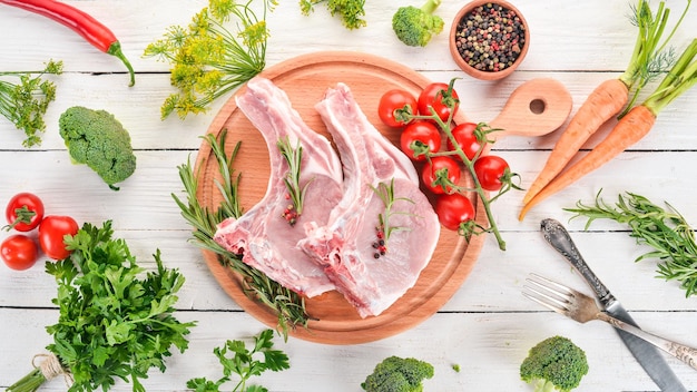 Bistecca cruda con l'osso con spezie e verdure su uno sfondo di legno vista dall'alto copia spazio