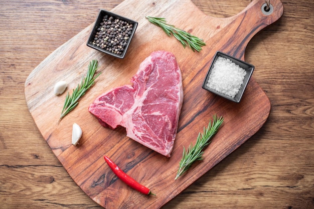 raw steak on a cutting board with herbs. Wooden background.