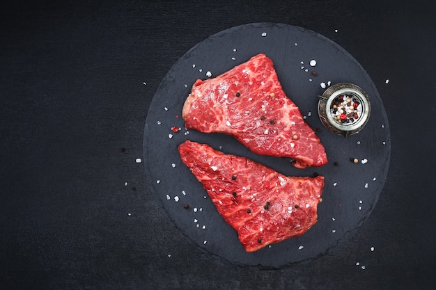 Raw steak on cutting board with rosemary and spices