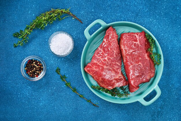 Raw steak on a cutting board with rosemary and spices