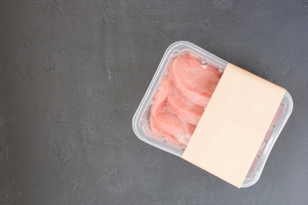 Raw steak, entrecote in plastic vacuum packaging on a black\
background. logo layout design.